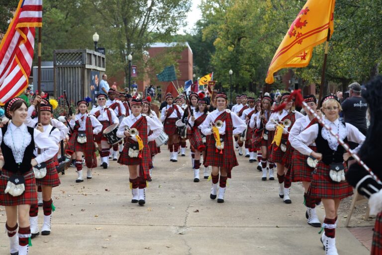 Pipe band in kilts marching with flags at the Arkansas Scottish Festival at Lyon College in Batesville